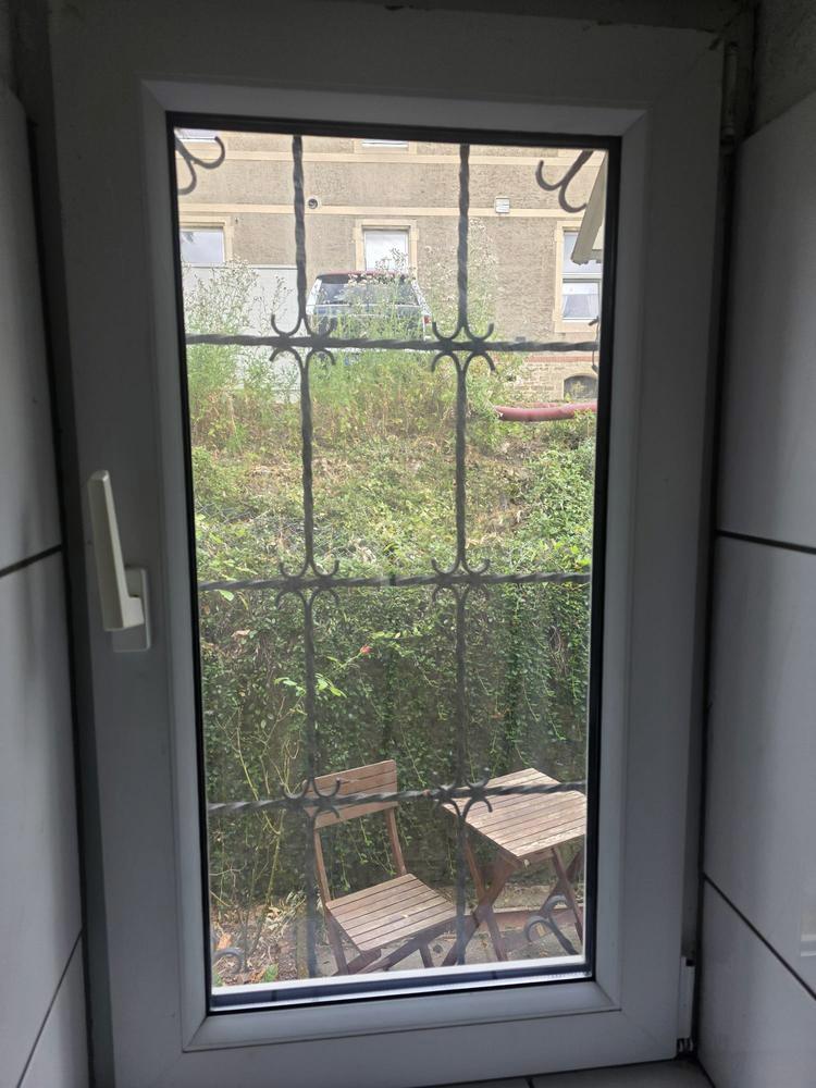 Neues Fenster hinter einem alten schmiedeeisernen Ziergitter