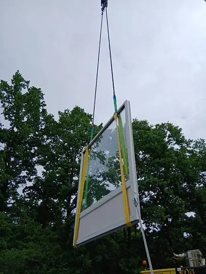 Ein neues Fenster wird per Kran zur Montage angehoben
