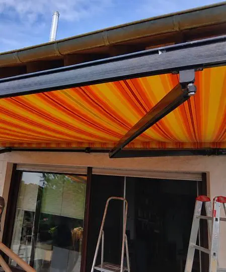 Markise mit orange-gelb gestreiftem Stoff